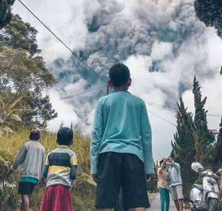 Warga lereng Merapi mengamati gumpalan asap hitam yang dikeluarkan gunung berapi tersebut