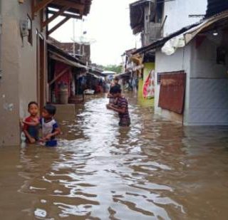 Sejumlah anak-anak bermain-main di genangan air banjir yang merendam wilayahnya.