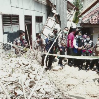 Sejumlah aparat kepolisian dan warga mengamati rumah yang roboh akibat tanah longsor, Minggu (28/2/2021)