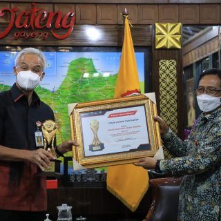 Kepala OJK Regional Jateng-DIY, Aman Santosa, menyerahkan piala dari OJK pusat kepada Gubernur Ganjar Pranowo