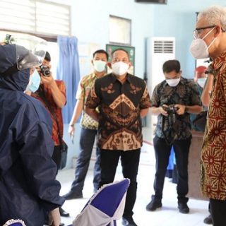 Gubernur Jawa Tengah, Ganjar Pranowo, berbincang dengan vaksinator (kiri) di Puskesmas Jaten I Kabupaten Karanganyar, Selasa (27/7)