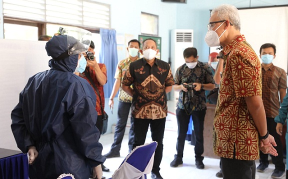 Gubernur Jawa Tengah, Ganjar Pranowo, berbincang dengan vaksinator (kiri) di Puskesmas Jaten I Kabupaten Karanganyar, Selasa (27/7)