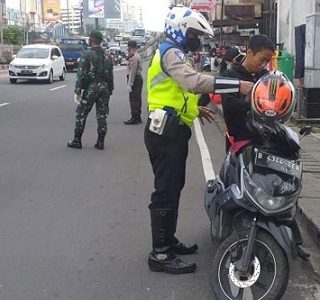 Petugas menjaga ruas jalan dalam  membatasi pergerakan masyarakat saat PPKM Darurat