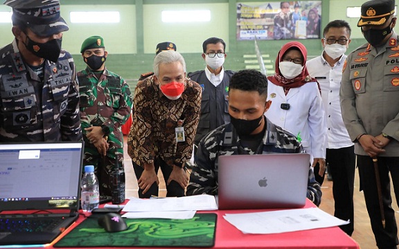 Gubernur Jateng Ganjar Pranowo berbincang dengan Letnan Always Tiris yang sibuk dengan laptopnya pada acara Serbuan Vaksinasi Covid-19 Koarmada II di Kabupaten Tegal, Rabu (25/8)