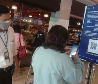 Petugas mengarahkan pemgunjung mal melakukan scan vaksinasi.