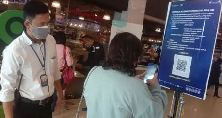 Petugas mengarahkan pemgunjung mal melakukan scan vaksinasi.