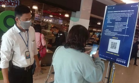 Petugas mengarahkan pemgunjung mal melakukan scan vaksinasi.