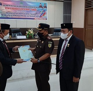 Sekda Kabupaten Boalemo Dr Sherman Moridu menyerahkan sertifikat lahan seluas 13.620 m2 dan Piagam Penghargaan kepada Kepala Kejaksaan Negeri Boalamo, Ahmad Muchlis SH MH dengan disaksikan Kajati Gorontalo Risal Nurul Fitri SH.