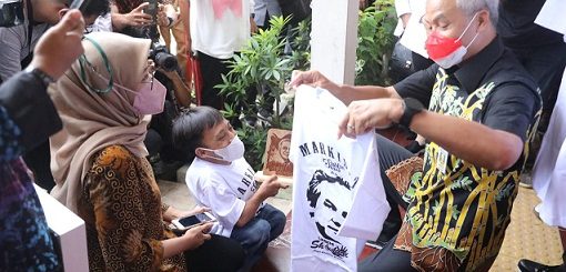 Awaludin, bocah penyandang disabilitas memberi kaos hasil produksinya kepada Gubernur Jateng, Ganjar Pranowo, saat meninjau vaksinasi anak dan simulasi pembelajaran tatap muka (PTM) di SLB N Tamanwinangun Kebumen, Rabu (12/1)