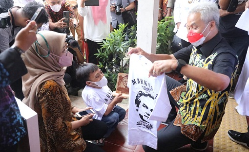 Awaludin, bocah penyandang disabilitas memberi kaos hasil produksinya kepada Gubernur Jateng, Ganjar Pranowo, saat meninjau vaksinasi anak dan simulasi pembelajaran tatap muka (PTM) di SLB N Tamanwinangun Kebumen, Rabu (12/1)