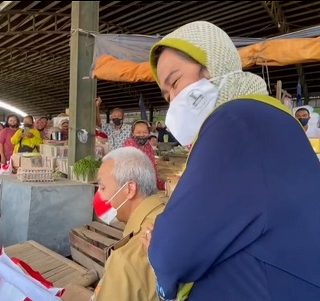 Gubernur Jateng Ganjar Pranowo dipijit pedagang telur asin saat duduk menunggu kedatangan Presiden Jokowi