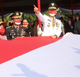 Gubernur Jateng Ganjar Pranowo bersama Wakil Gubernur Jateng Taj Yasin Maimoen, Sekda Jateng Sumarno membentangkan bendera merah putih ukuran besar pemberian dari para buruh migran saat peringatan upacara HUT 77 RI di Lapangan Pancasila Semarang, Rabu (17/8/2022)
