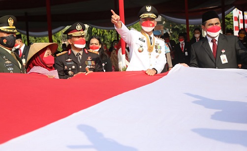Gubernur Jateng Ganjar Pranowo bersama Wakil Gubernur Jateng Taj Yasin Maimoen, Sekda Jateng Sumarno membentangkan bendera merah putih ukuran besar pemberian dari para buruh migran saat peringatan upacara HUT 77 RI di Lapangan Pancasila Semarang, Rabu (17/8/2022)