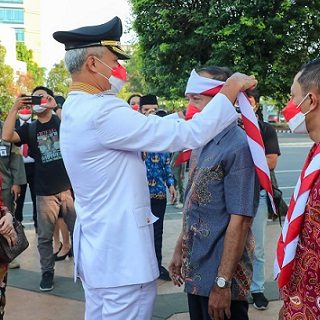 Gubernur Jawa Tengah Ganjar Pranowo menyematkan hasduk merah putih di kepala salah seorang eks napiter, yang mengikuti upacara peringatan Hari Ulang Tahun (HUT) ke 77 Republik Indonesia di Lapangan Pancasila Simpanglima, Kota Semarang, Rabu (17/8/2022)