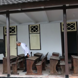 Capres nomor urut 3 Ganjar Pranowo memperhatikan bangku-bangku kelas di rumah pengasingan Bung Hatta, di Banda Neira, pulau kecil di Maluku, Selasa (30/1/2024)